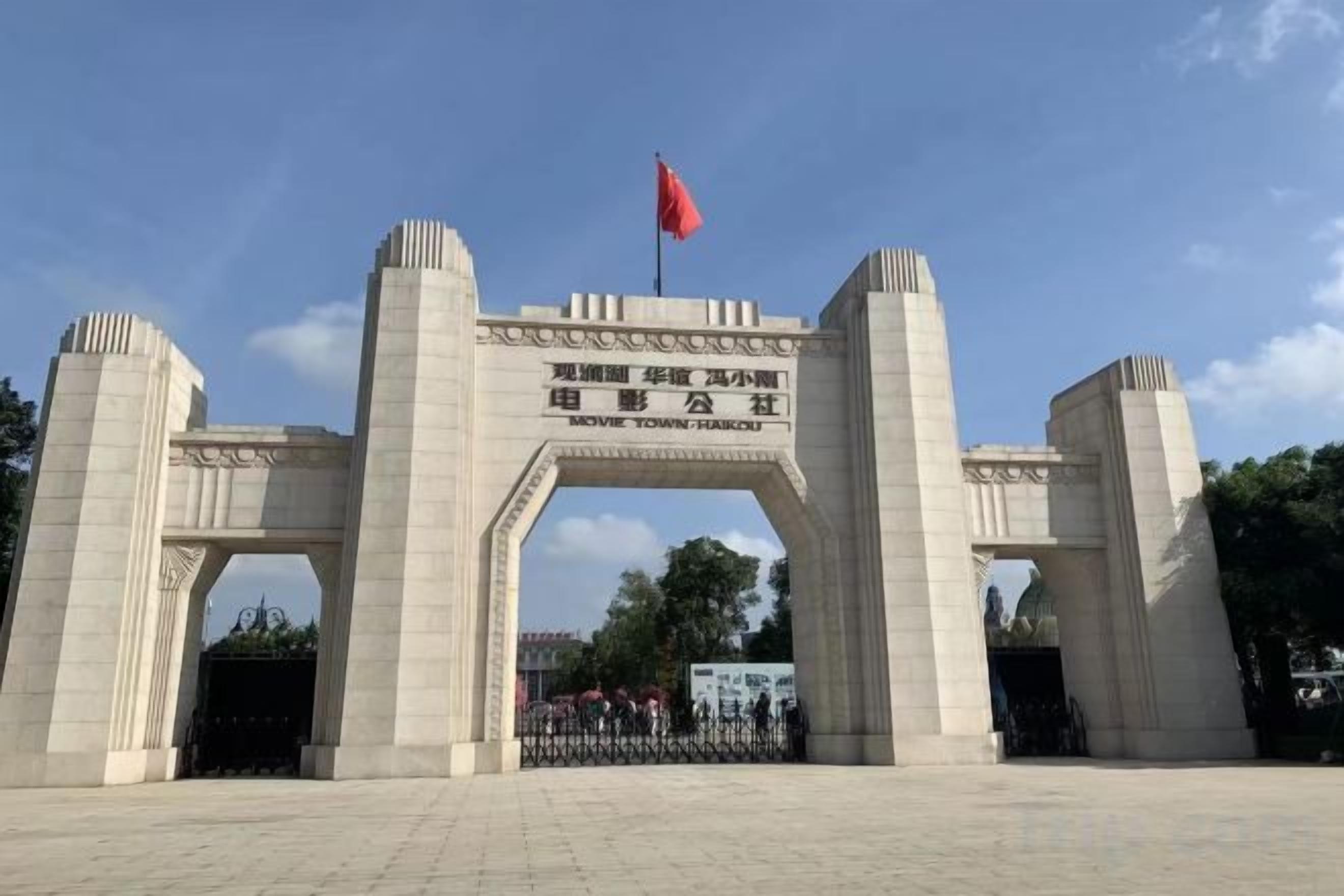 A large stone archway with a flag on top, leading to a gated entrance.