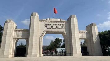 A large stone archway with a flag on top, leading to a gated entrance.