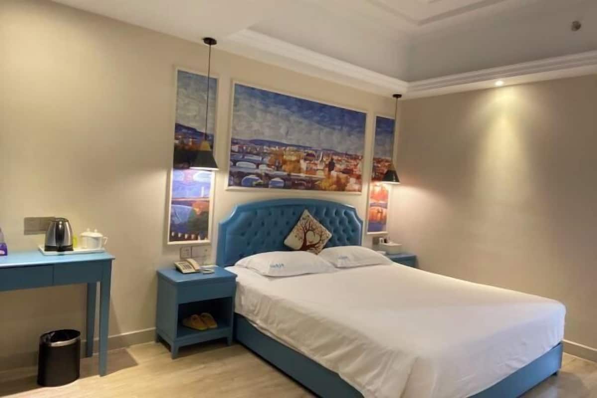 Ein Schlafzimmer mit einem großen Bett, einem Nachttisch, einem Schreibtisch und einer Mülltonne.