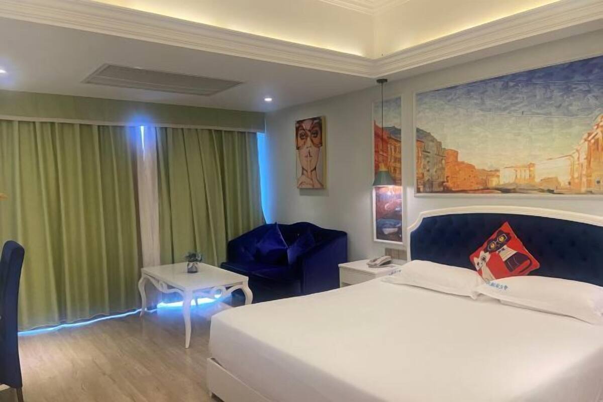 Ein Hotelzimmer mit Bett, Schreibtisch, Stuhl und einem Gemälde an der Wand.