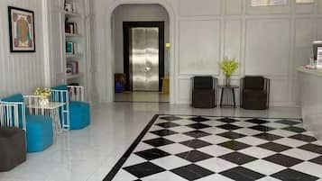A lobby with a checkered floor, a reception desk, and a seating area with blue chairs.