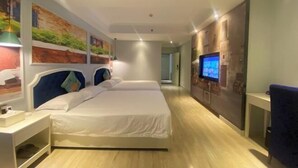 A hotel room with a large bed, a TV on the wall, and artwork on the walls. - Haikou Dream House Hotel (Nansha Road) (Haikou)