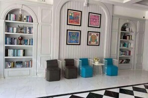 A room with a checkered floor, a bookshelf, a framed artwork, and a small table with chairs. - Haikou Dream House Hotel (Nansha Road) (Haikou)