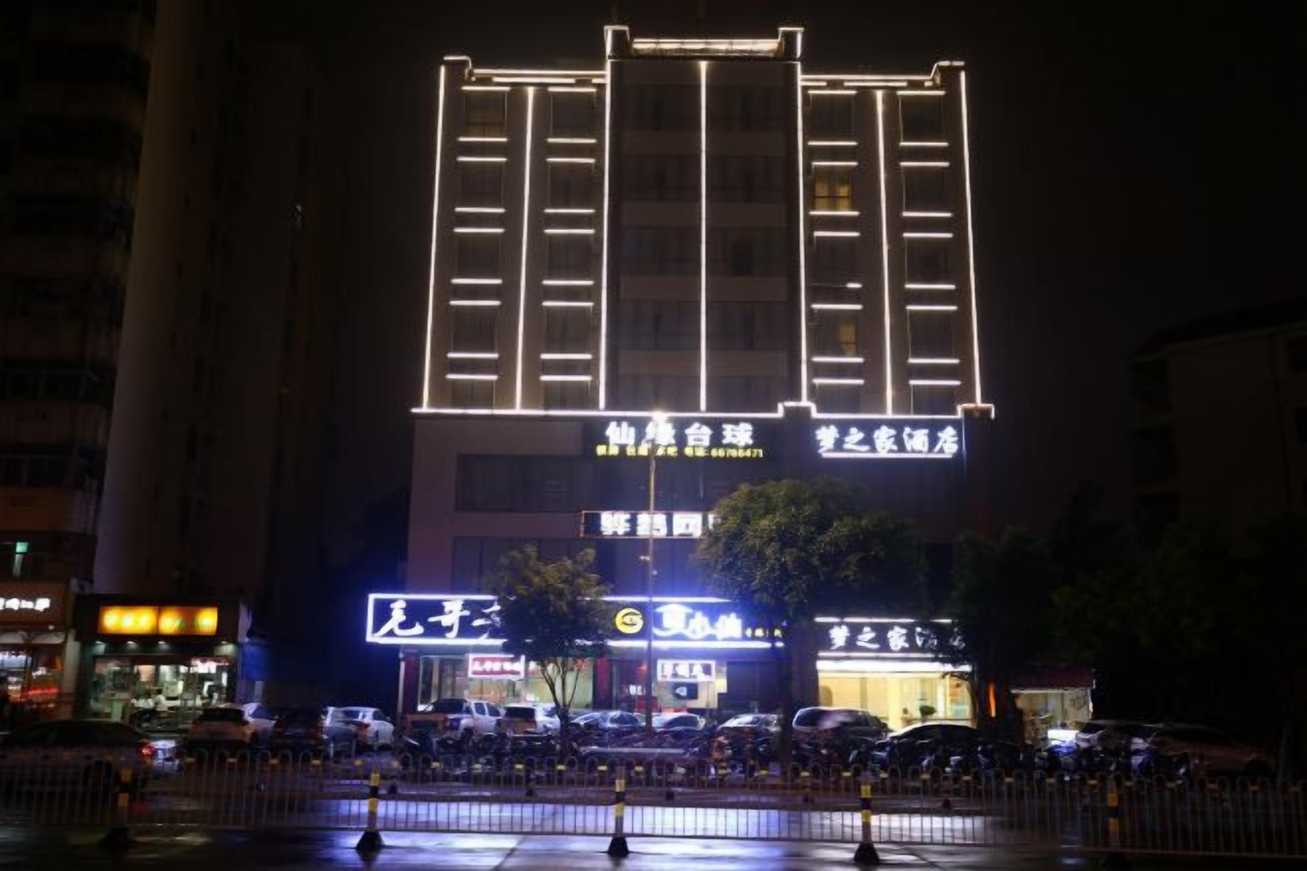 A building with illuminated signage, a visible entrance, and a parking area in front.