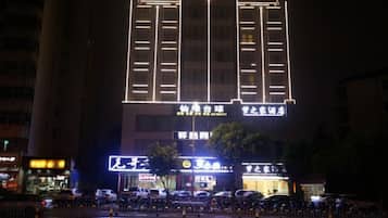 A building with illuminated signage, a visible entrance, and a parking area in front.