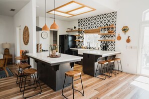 Una cocina moderna con una isla central, iluminación colgante y un salpicadero con diseño.