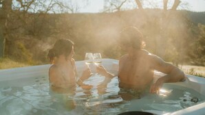 Two people in a hot tub with a clear view of trees and a sunset in the background. - Sunset Glow *Hidden Meadow*BBQ HotTub by Casa Oso (Oakhurst)