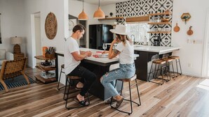Una cucina moderna con isola centrale, illuminazione a sospensione e backsplash decorato.