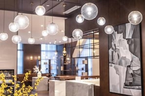 A modern interior with hanging spherical lights, marble countertops, and a large abstract painting. - Hanrun 1882 Hotel (Nanjing)