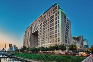 A high-rise hotel with a prominent entrance and a view of the city skyline. - Hanrun 1882 Hotel (Nanjing)
