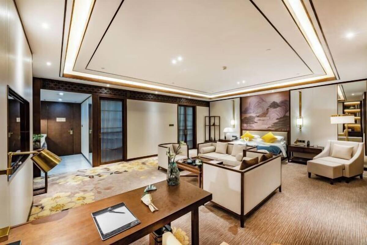 Una habitación de hotel moderna con sala de estar, una mesa de comedor y una cama grande.