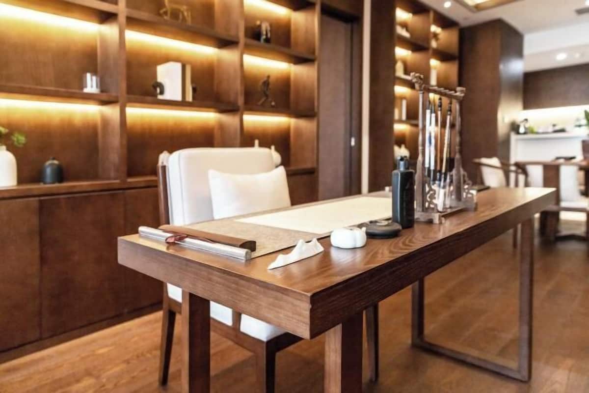 Un espacio de oficina moderno con un escritorio de madera, una silla blanca y estanterías con diversos objetos.