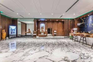 A spacious lobby with a marble floor, a reception desk, and a seating area with bar stools. - Hanrun 1882 Hotel (Nanjing)