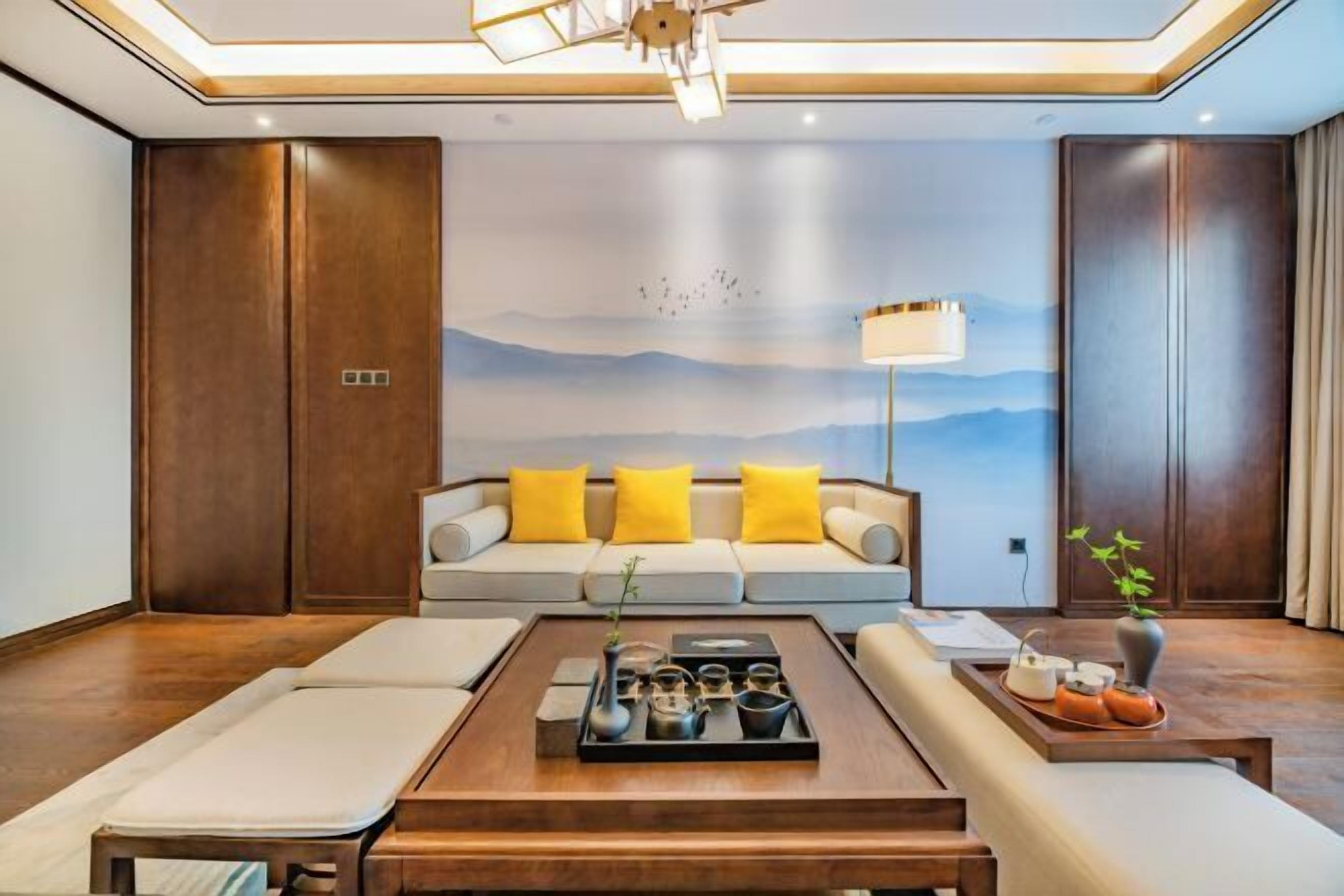 A modern living room with a sofa, coffee table, and a mural of mountains.