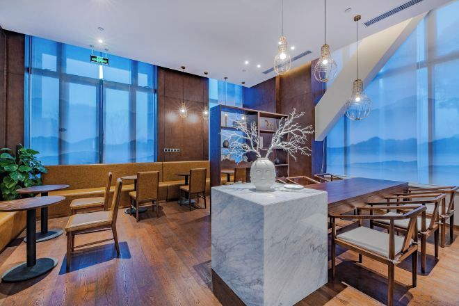 A modern interior with a marble island, wooden furniture, and large windows offering a view.