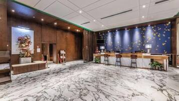 A hotel lobby with a reception desk, bar area, and seating.