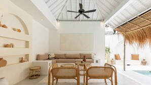 A modern living room with a sofa, two wicker chairs, a coffee table, and a ceiling fan. - Villa Casa Bocami Canggu By Azure Near Finns (Canggu)