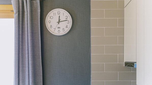 Reloj sobre una pared con textura y un revoque de azulejos.