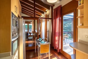 Cozinha moderna com eletrodomésticos embutidos, área de refeições com mesa e cadeiras, e vista para uma piscina através de grandes janelas.