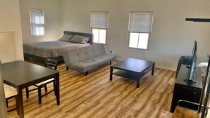 Una habitación con cama, sofá, mesa y televisor.