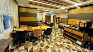 Un área de comedor moderna con piso de diseño geométrico, vigas de madera en el techo y una máquina de café Nescafé.