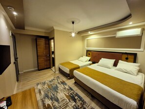 Una habitación de hotel con dos camas, un armario de madera, un espejo y una lámpara en el techo.