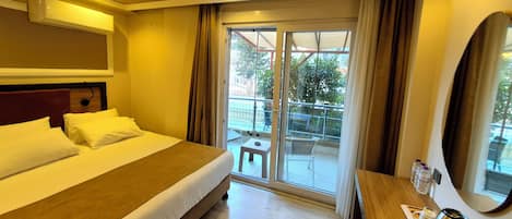 Habitación de hotel con cama, escritorio con hervidor, una silla y vistas al exterior.