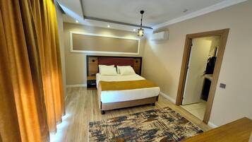 A modern hotel room with a large bed, a wooden headboard, a patterned rug, and a ceiling light fixture.