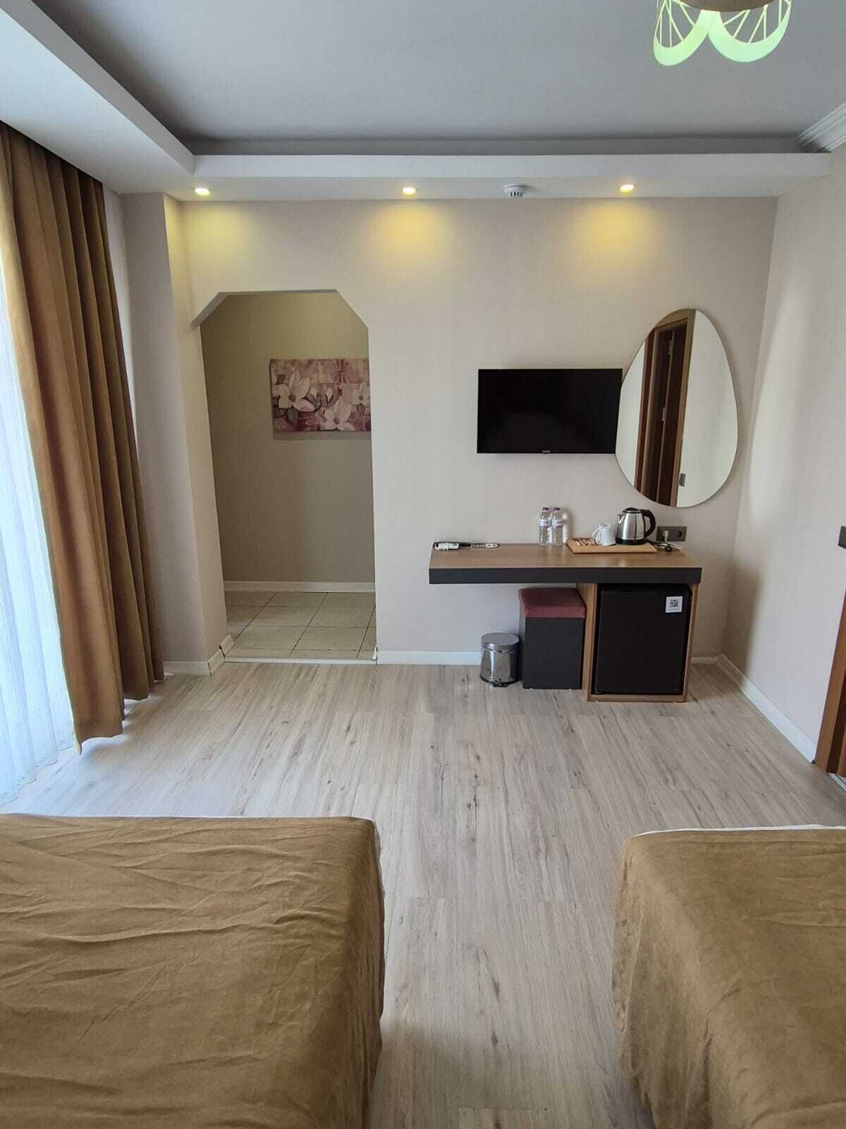Une chambre d’hôtel avec deux lits, un bureau avec un miroir, une télévision et un espace douche.