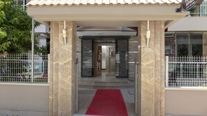 Entrada de hotel con alfombra roja, techo de tejas y un cartel que dice Toprak Apart.