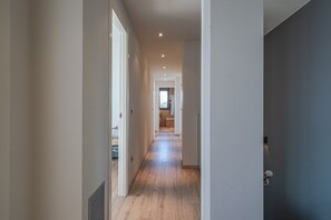 Un pasillo estrecho con suelo de madera y paredes blancas.
