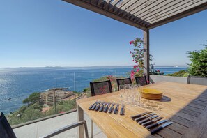 A wooden table set for dining with a view of the sea and distant mountains. - VILLA VELAZQUEZ Roses (Rosas / Roses)