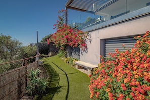 Una casa moderna con un césped cuidado, un banco de madera y plantas florecientes.