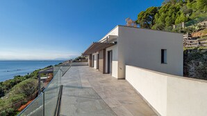 Un edificio moderno con balcón de cristal que da a la costa.
