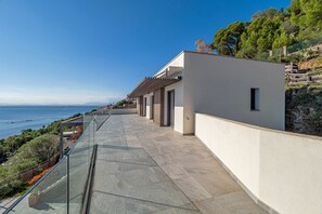 A modern building with a glass balcony overlooking a coastal area. - VILLA VELAZQUEZ Roses (Rosas / Roses)