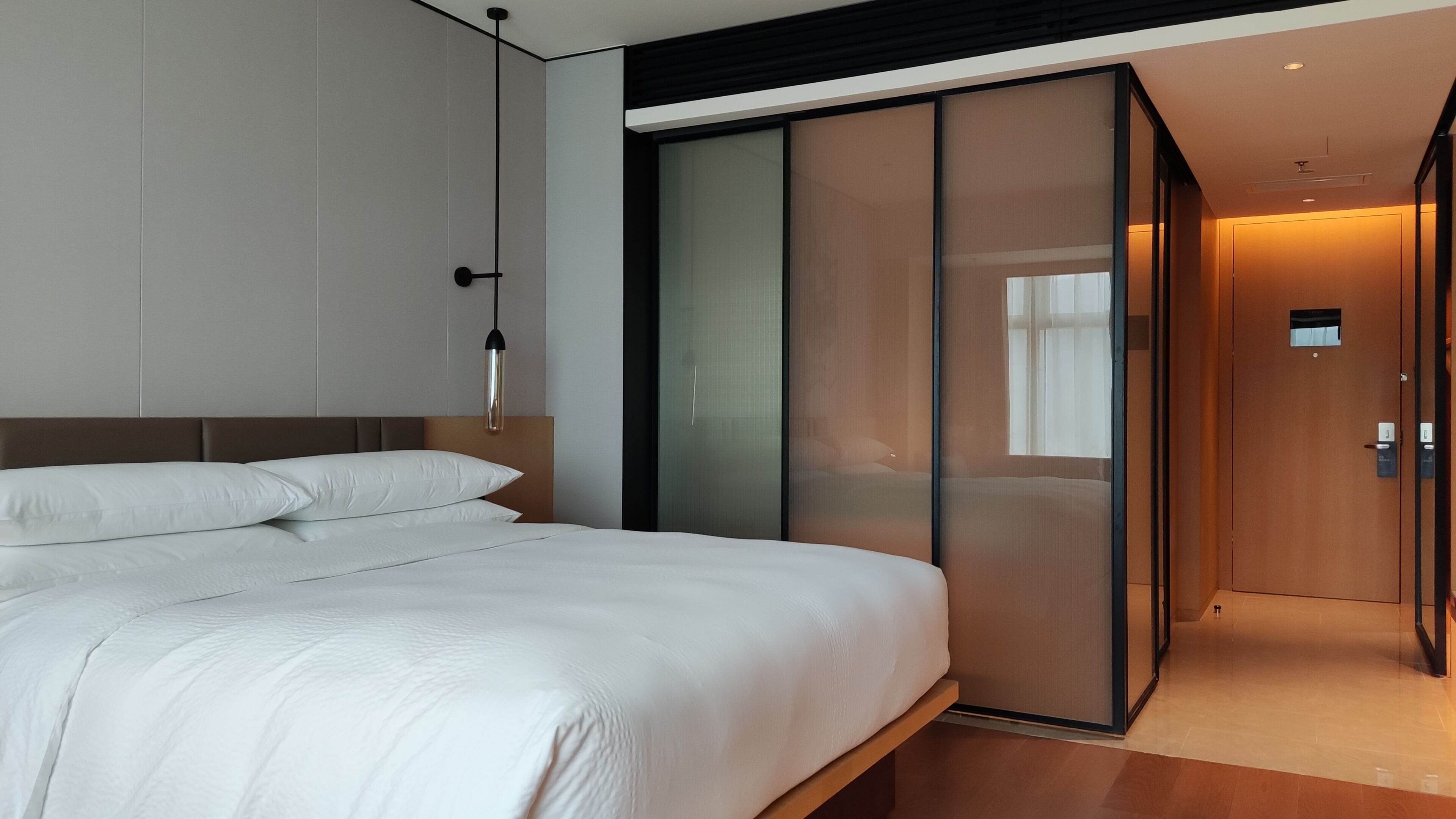 Un dormitorio moderno con una cama grande, una puerta corrediza de vidrio y un aplique de techo.