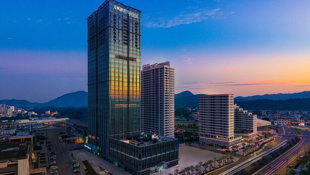 A modern high-rise hotel with a glass facade, surrounded by a well-maintained urban area with roads and other buildings. - Fairfield by Marriott Shenzhen Shenshan Special Cooperation Zone (Shanwei)