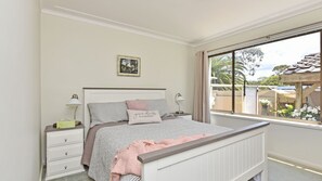 Quarto com cama, mesas de cabeceira, janela com vista exterior e quadro pendurado na parede.