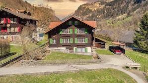 A traditional chalet with a sloped roof, a wooden facade, and green shutters, surrounded by a mountainous landscape. - THE Best Valley View •  Swiss Charm • Free Parking (Lauterbrunnen)