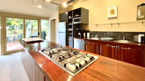 A modern kitchen with a central island, stainless steel appliances, and a view to a patio.