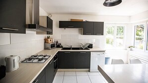 Una cocina moderna con armarios oscuros, estufa a gas, microondas y lavavajillas.