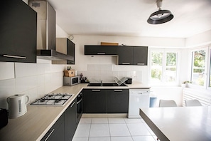 A modern kitchen with dark cabinets, a gas stove, a microwave, and a dishwasher. - Rental T3 + terrace in house "Le Ripaille (Thonon-les-Bains)