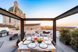 A rooftop dining area with a table set for six, surrounded by white sofas and potted plants. - Apartment with terrace in the centre, 300 metres from the beach, Trapani (Trapani)