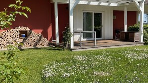 Une maison à l’extérieur rouge, avec un porche blanc et un toit équipé de panneaux solaires.