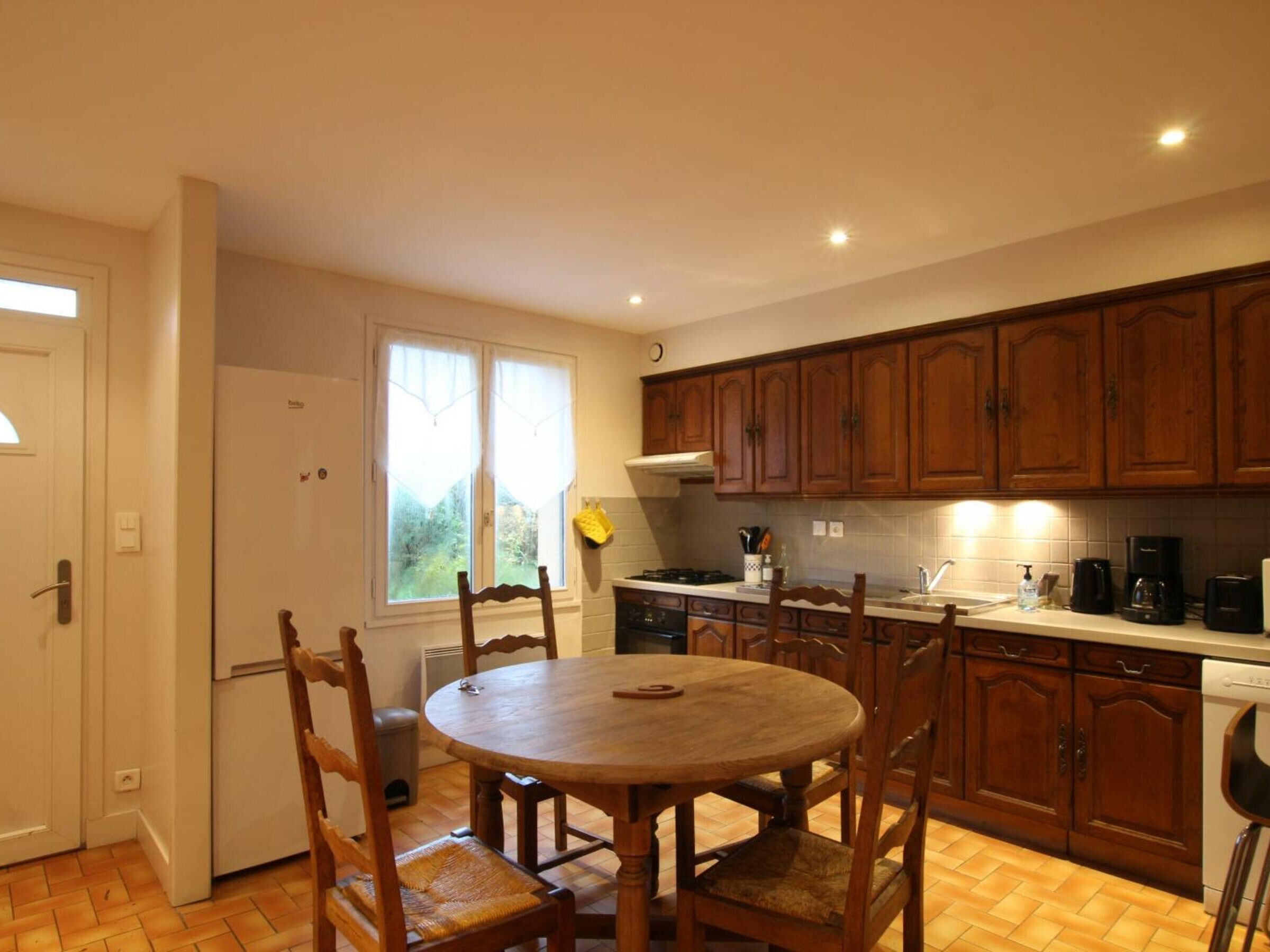 A kitchen with wooden cabinets, a round dining table, and chairs.