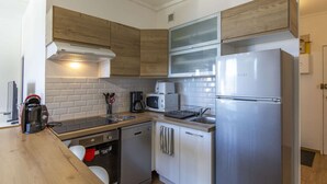 Une cuisine moderne dotée d’appareils électroménagers en acier inoxydable, de meubles en bois et d’un four à micro-ondes encastré.
