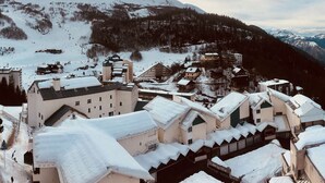 Un village de montagne enneigé, avec des bâtiments traditionnels et une piste de ski.