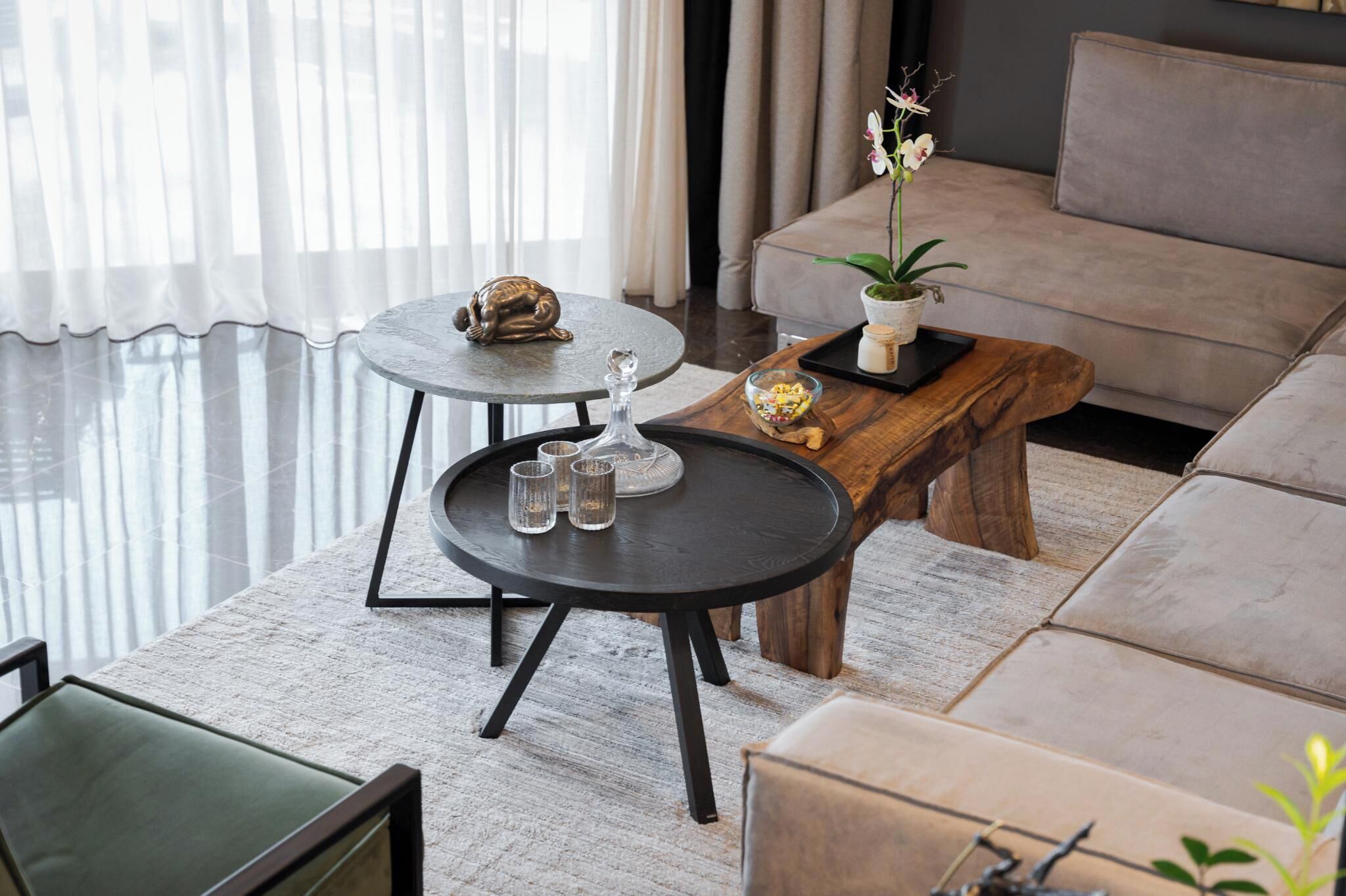 Un salon moderne avec un canapé, deux tables rondes et une table basse.