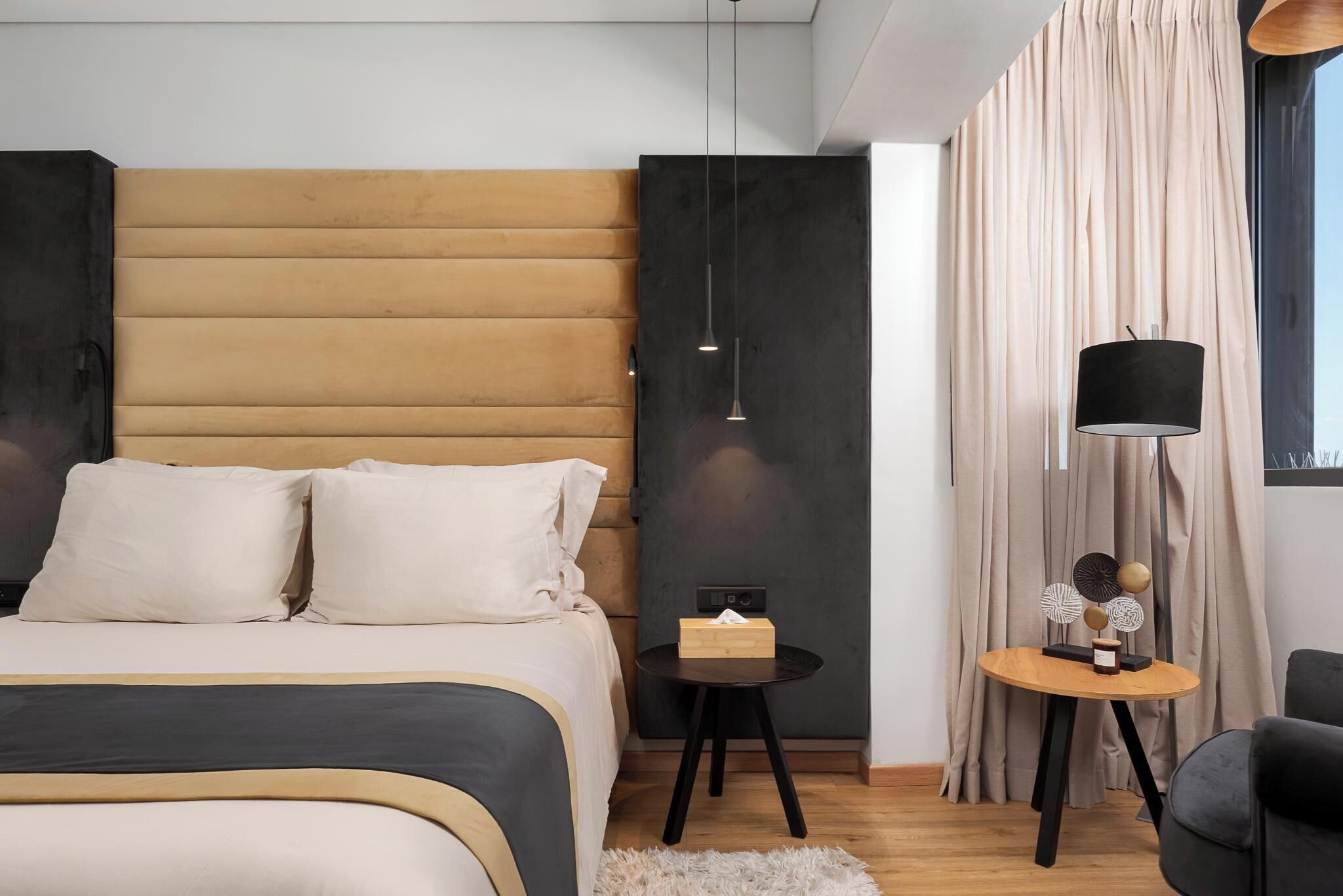 A modern bedroom with a bed, bedside table, lamp, and curtains.