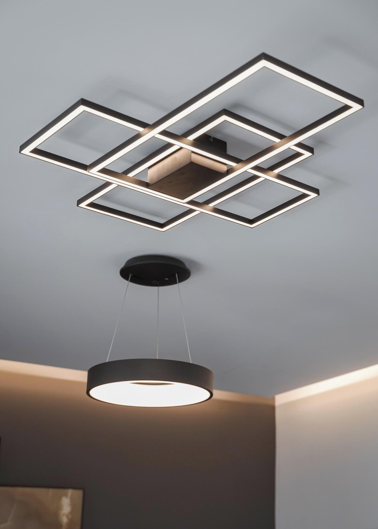 Eine moderne Deckenleuchte mit geometrischen Formen und einer runden Pendelleuchte darunter.